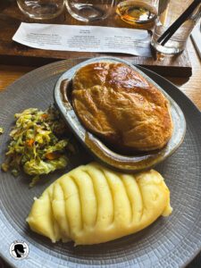 Dishes to try in Scotland - picture of a steak pie with mashed potatoes, and slaw.