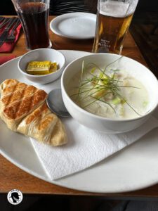 Dishes to try in Scotland - a picture of Cullen Skink.  A bowls of soup consisting of smoked haddock, onions and potatoes, accompanied by a croissant.