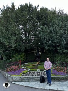 Picture of the Old Man in A Hat (without his hat) in front of a topiary clock at the Interlaken Casino.
